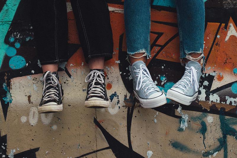 Teenagers legs dangling over graffitied wall